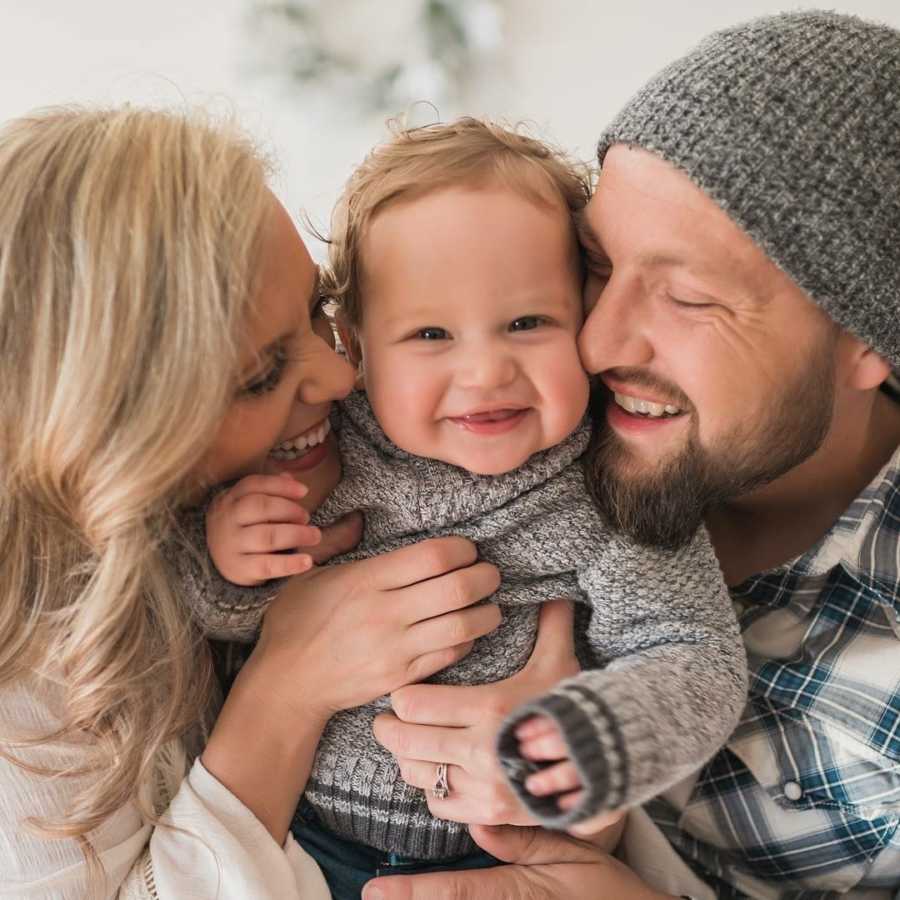 Husband and wife smiles as the hold adopted baby boy