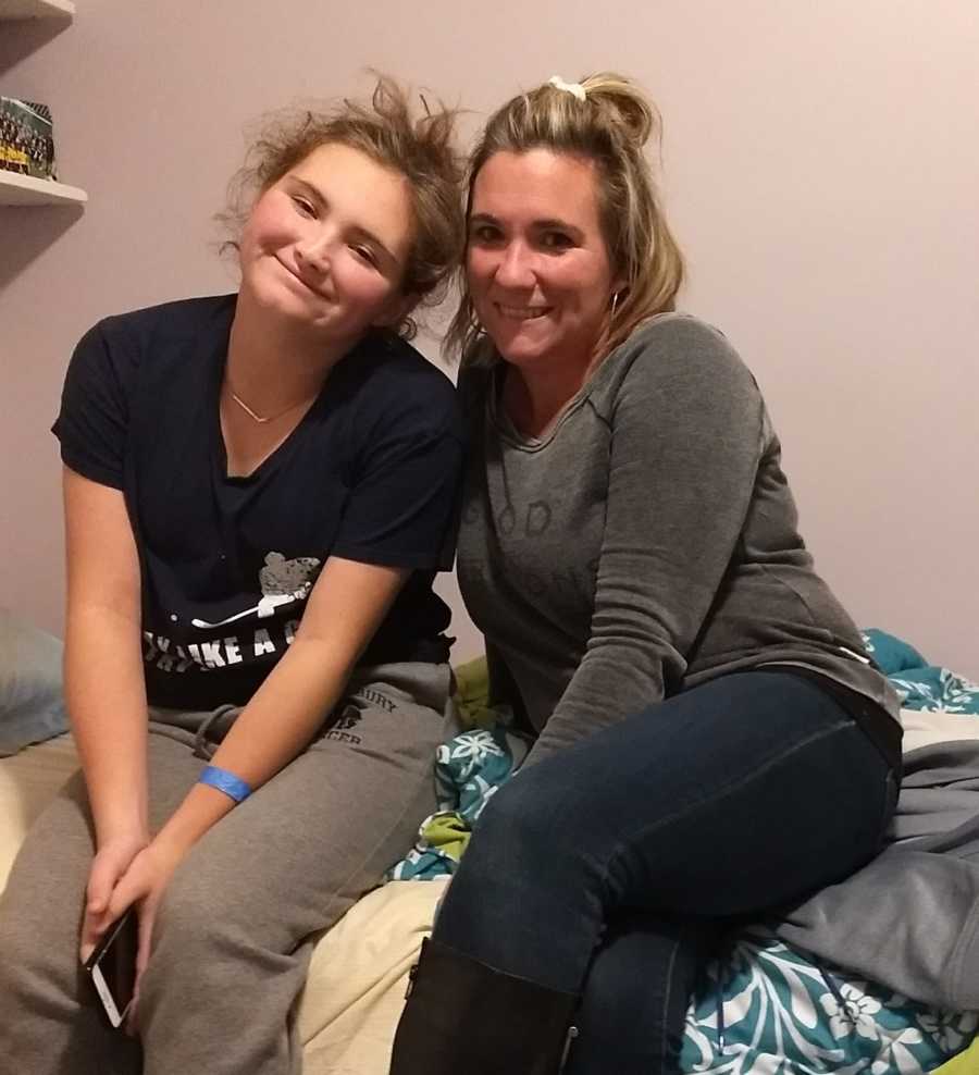 Mother who is a recovered alcoholic sits on bed with teen daughter 