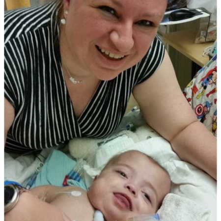 Mother smiles over baby son who lies in PICU