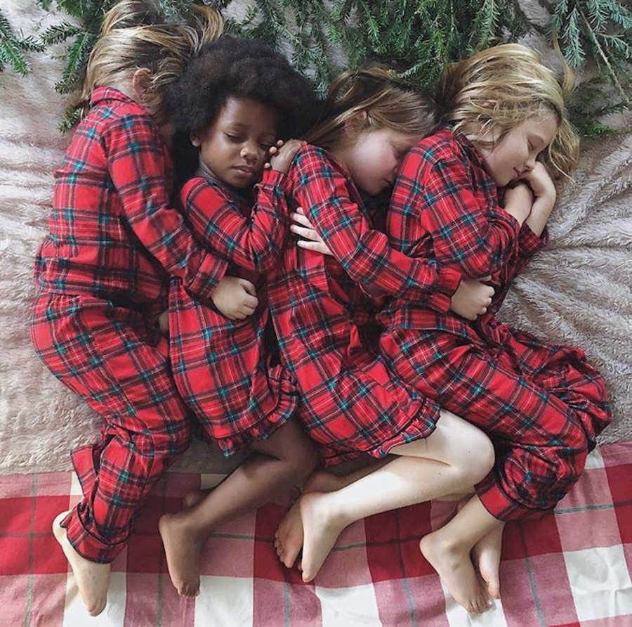 Siblings lay on their sides snuggled up to one another in matching red plaid pj's