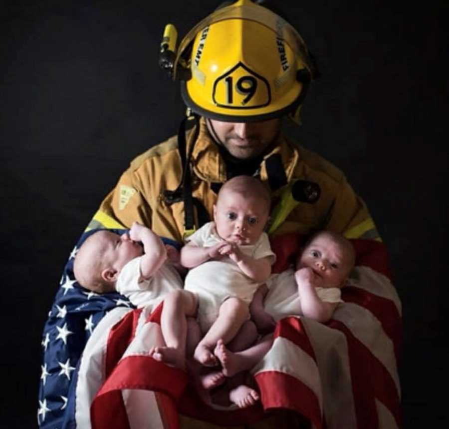 Firefighter with Chiari Malformation holds triplets in his arms along with American Flag