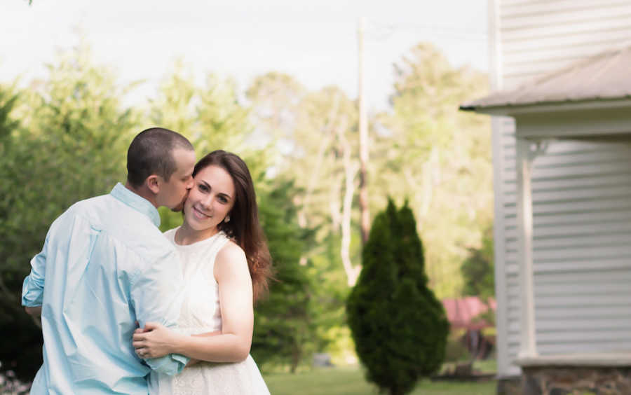 Husband holds and kisses wife who miscarried outside their home