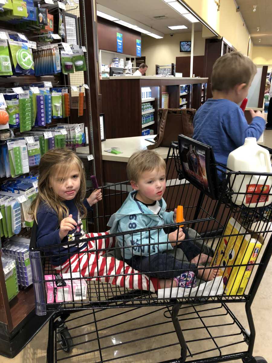 Three children sit in shopping cart at grocery store