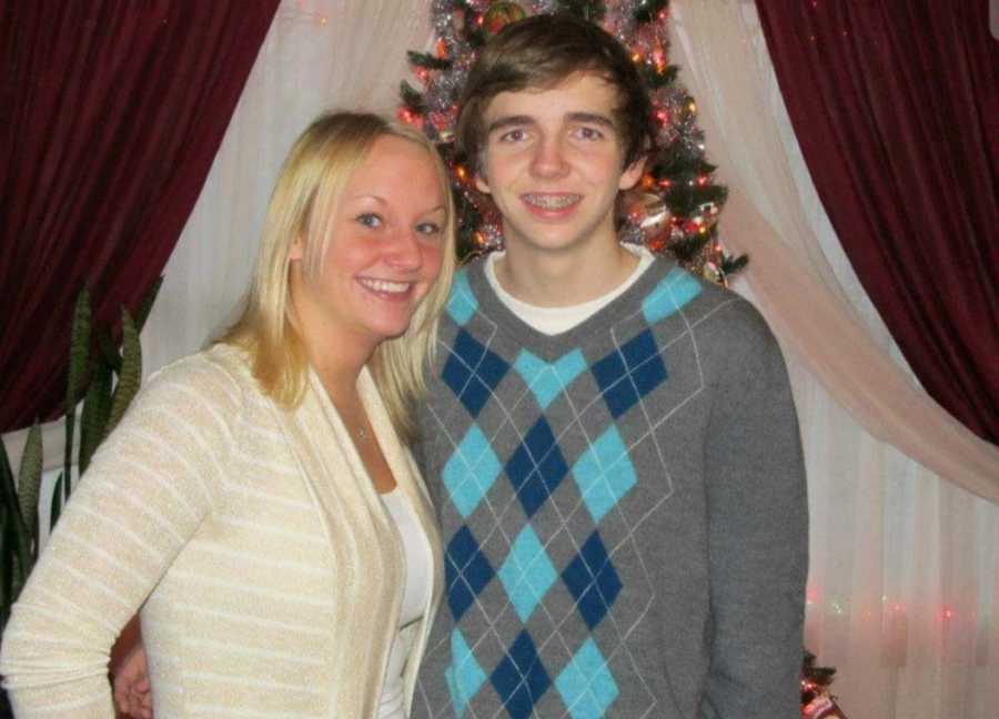Woman smiles beside brother who will become addicted to drugs in front of Christmas tree