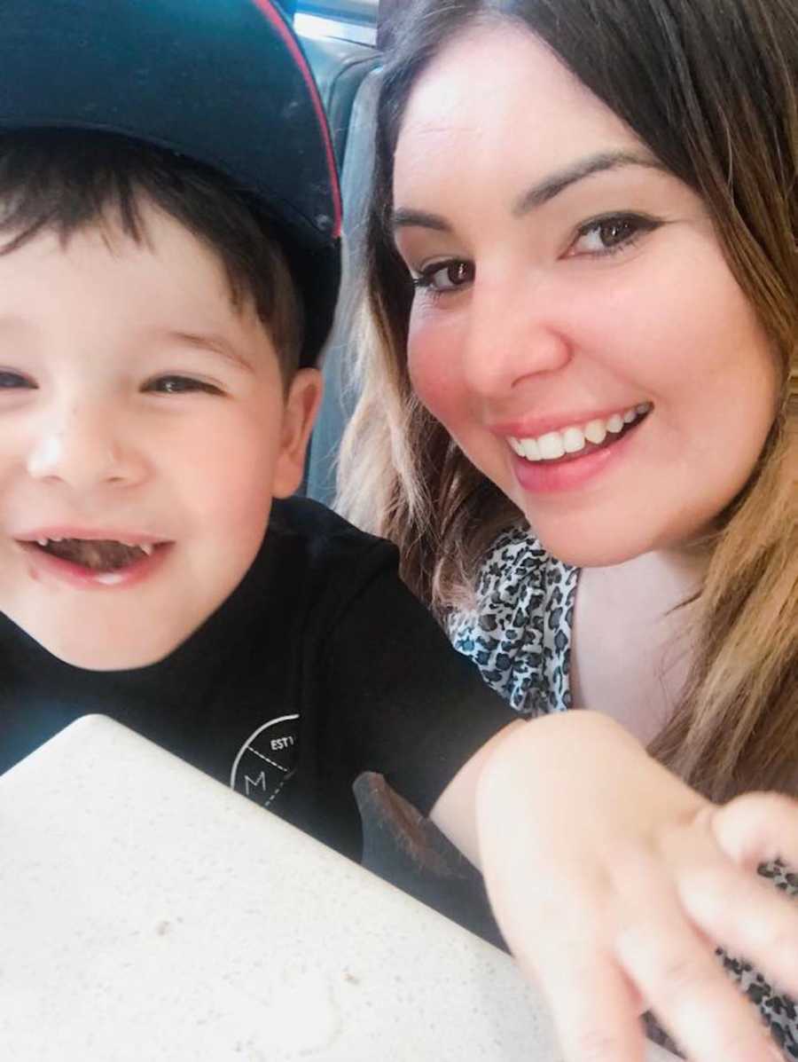 Mother smiles in selfie with young son who smiles with missing teeth