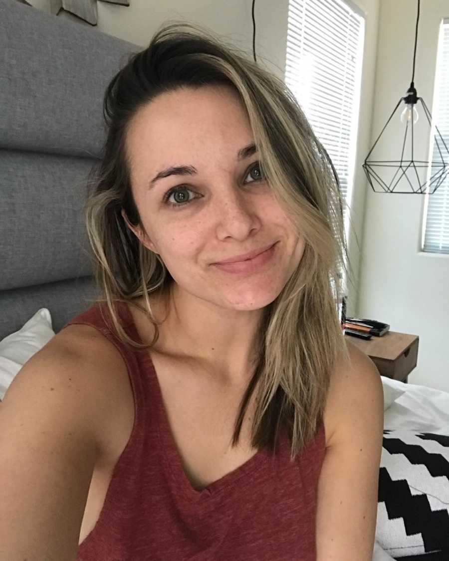 Woman who wants to fight to overcome PTSD smiles in selfie while sitting in bed