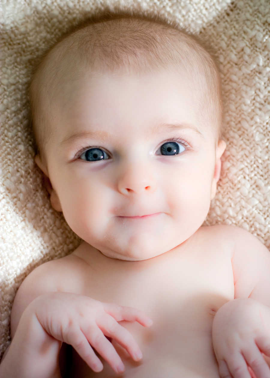 Little girl lays on her back with hands held to her chest