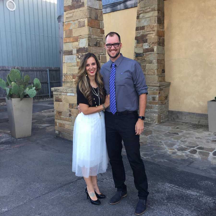 Husband and wife who are going to adopt stand smiling outside in semi-formal clothes