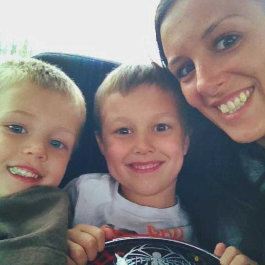 Mother smiles in selfie beside her two young sons