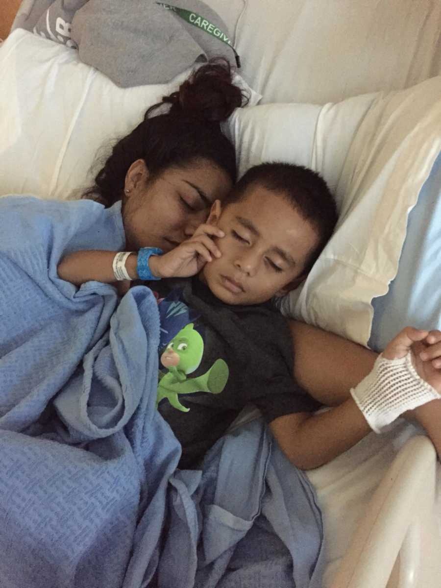 Mother lays in hospital bed with son who has swollen spleen