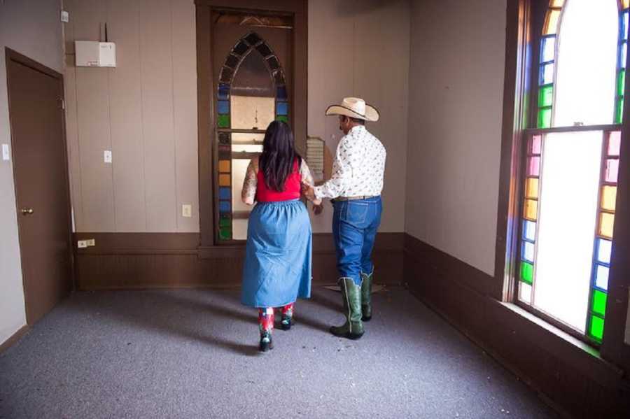 Husband and wife hold hands as they walk in hall of church