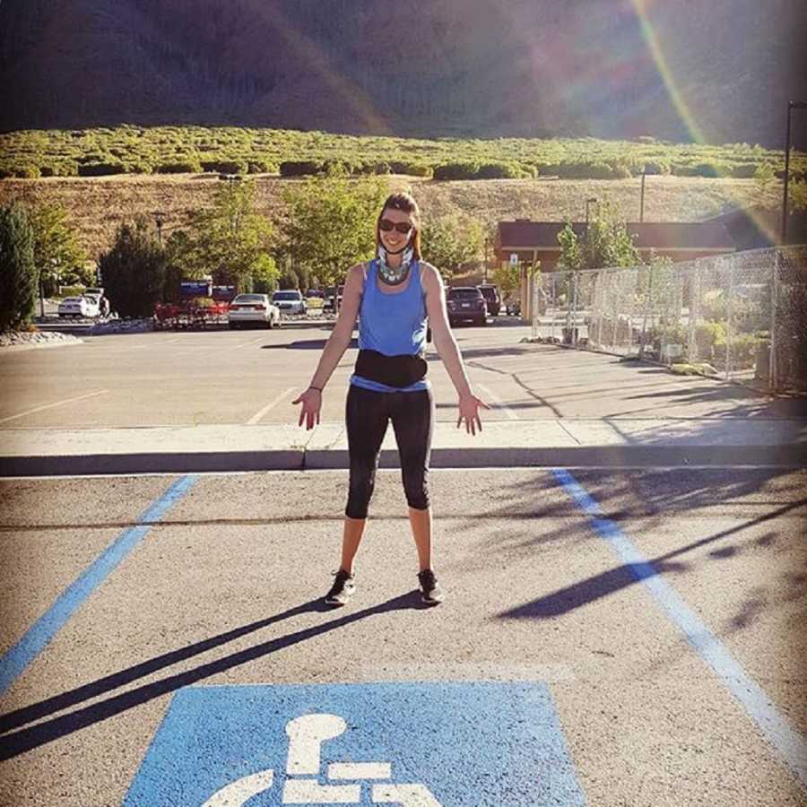 Young woman with Ehlers-Danlos Syndrome stands outside in handicap parking spot with neck brace on