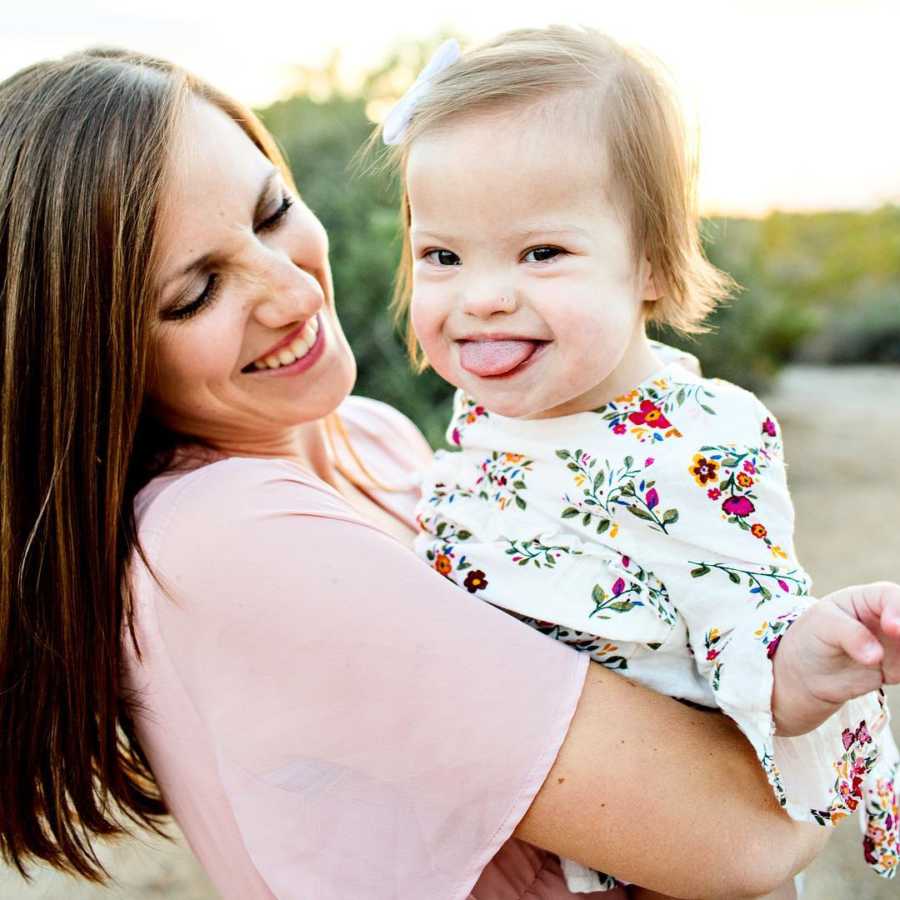 Mother smiles at daughter with down syndrome and heart defect she holds