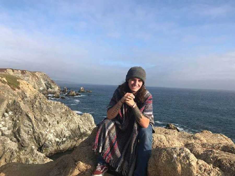 Young man who has since passed from drug overdose sits on cliff by body of water