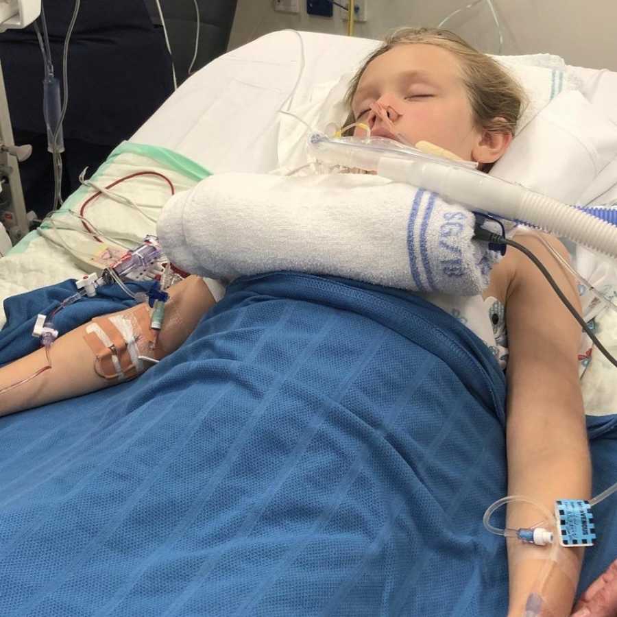Little girl in coma laying in hospital bed with wires and IV's attached all over her