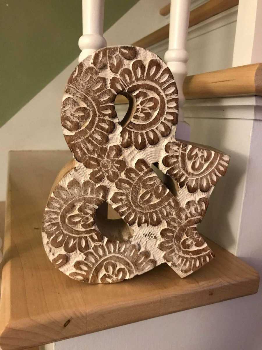 Wooden "and" symbol sitting on staircase to remind woman to live and love