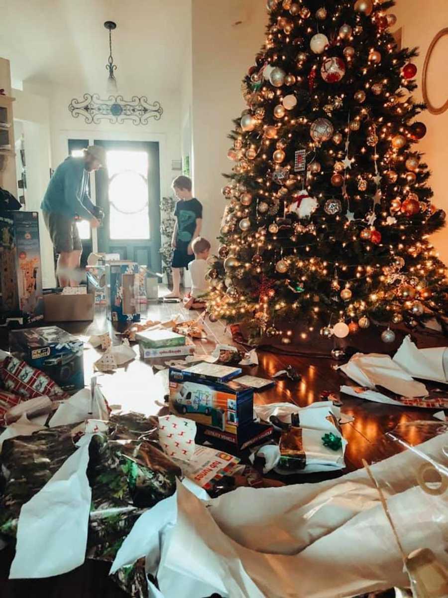 Floor of home covered in opened presents beside Christmas tree