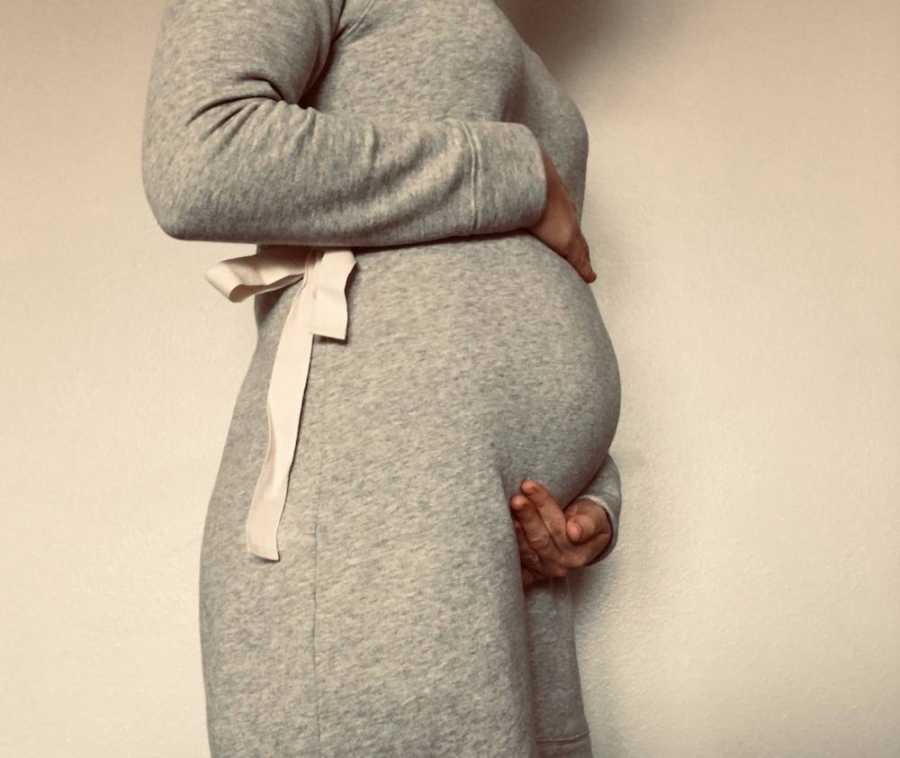 Side view of pregnant woman holding her stomach