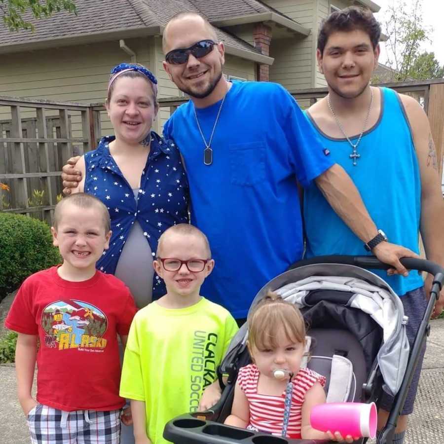 Pregnant woman stands beside husband who has since passed, teen, and three young children