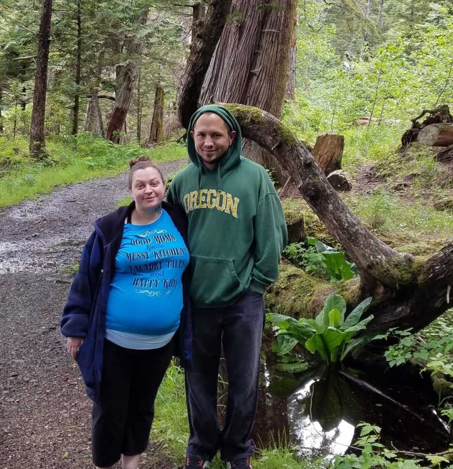 Wife stands in path of woods beside husband who has since passed