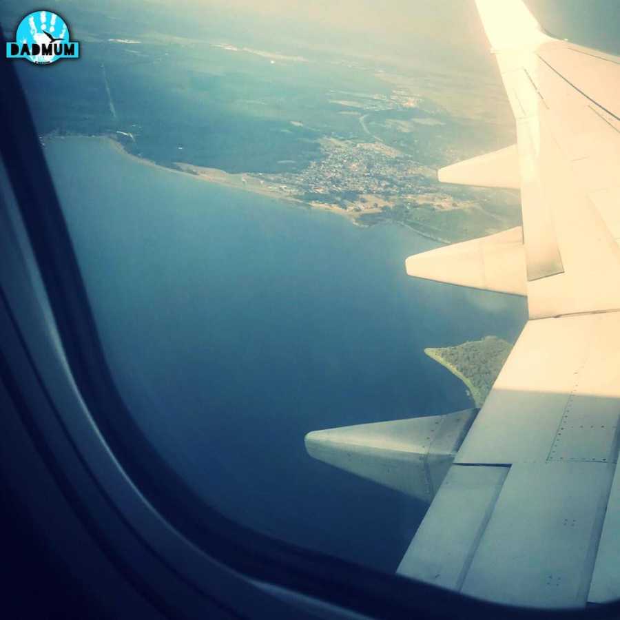 View from airplane window that shows wing of plane and body of water