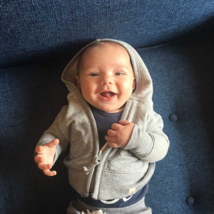 Baby smiles as he lies on couch on his back