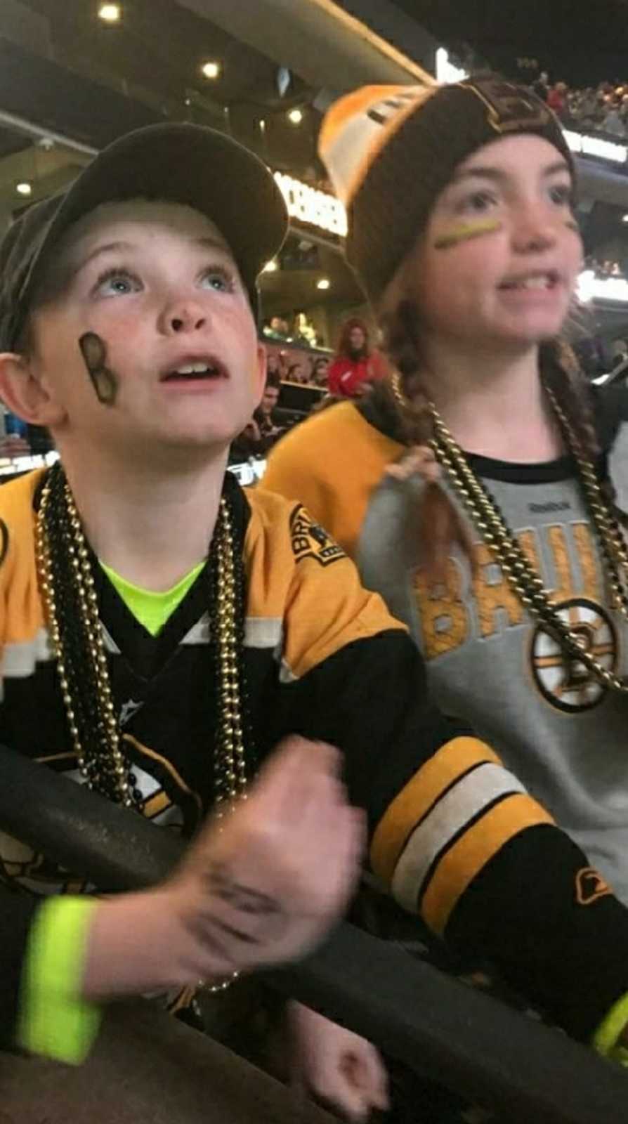Young boy and sister smile as the watch Boston Bruins game