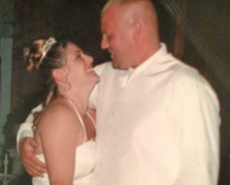 Bride and groom smile as they hold each other 