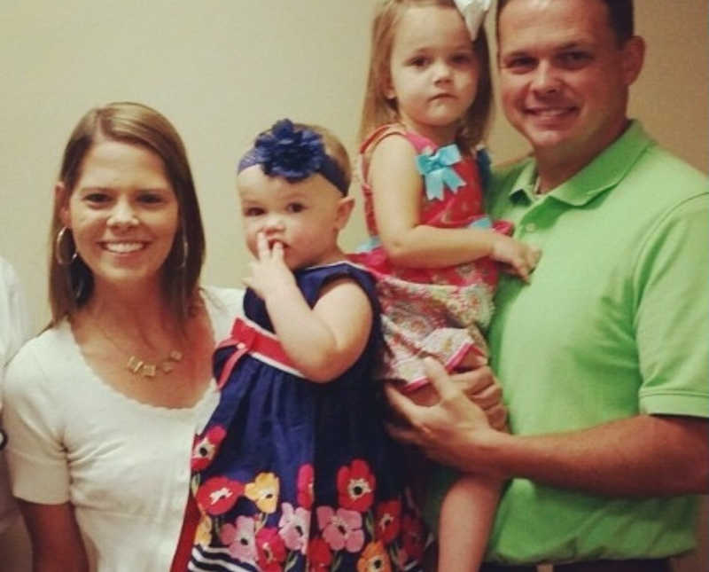 Husband and wife smile with their biological daughter and adopted daughter