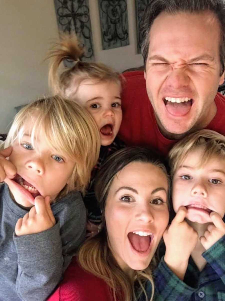 Mother smiles in selfie with husband and three kids who make silly faces