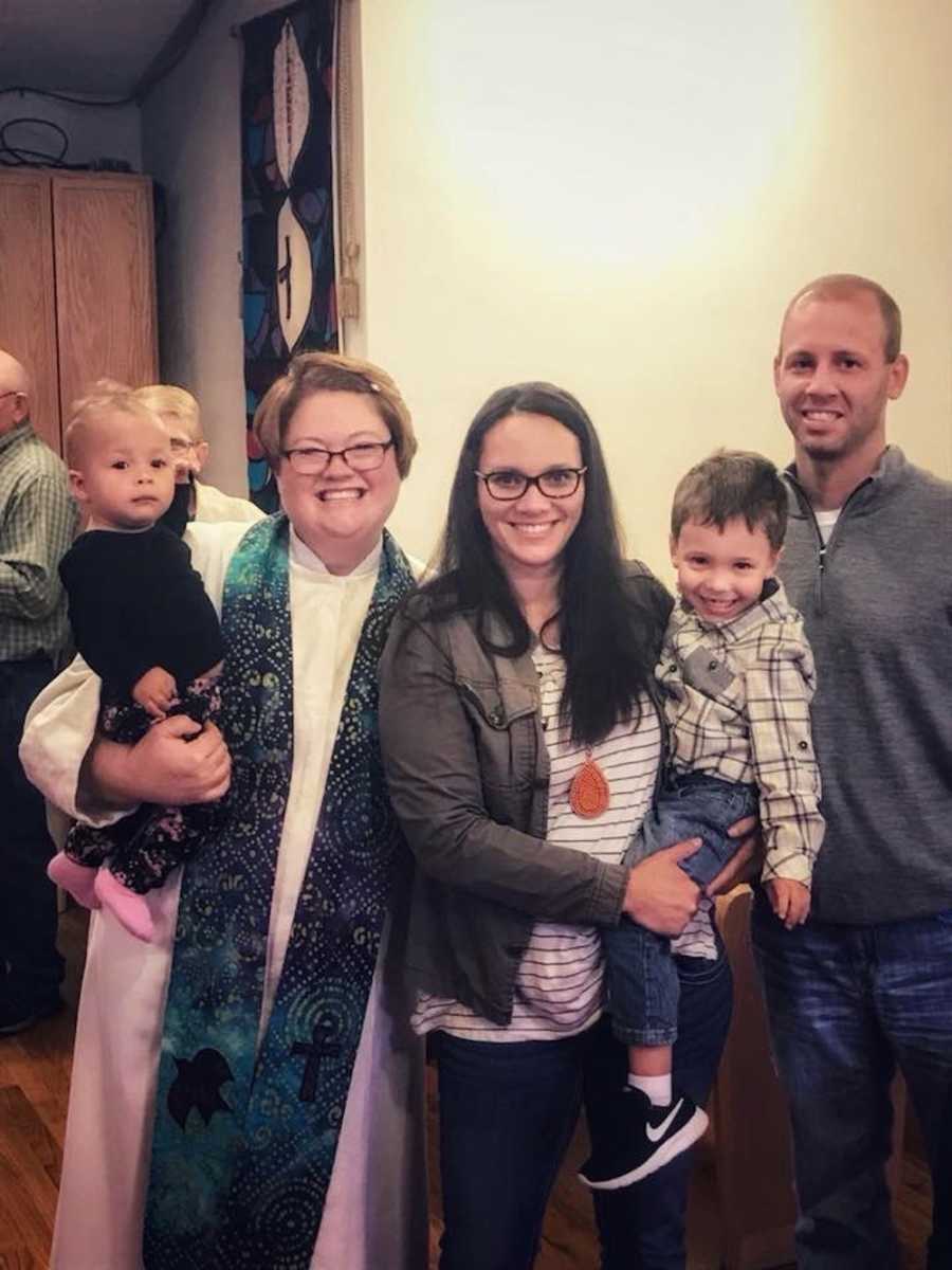 Woman stands beside husband holding pastor's adopted son beside pastor who holds other adopted son