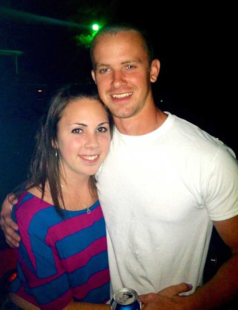 Boyfriend and girlfriend stand arm in arm smiling