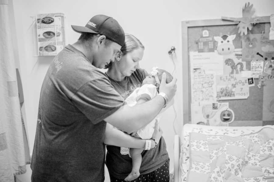 Mother and father stand side by side in hospital room holding baby with Biliary Atresia who would soon pass away