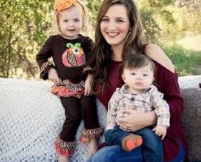 Woman who used to be abused smiles outside with baby boy on her lap and little girl at her side