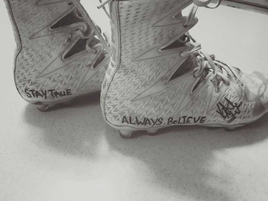 Close up of football cleats that have words, "Stay True" and "Always Believe" written on them