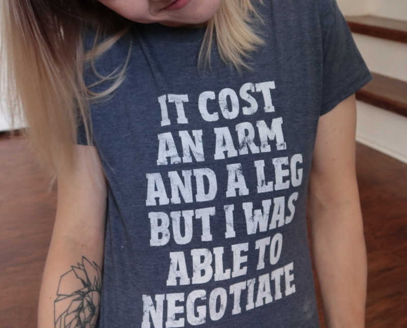 Close of up woman wearing t-shirt that says, "it cost an arm and a leg but I was able to negotiate