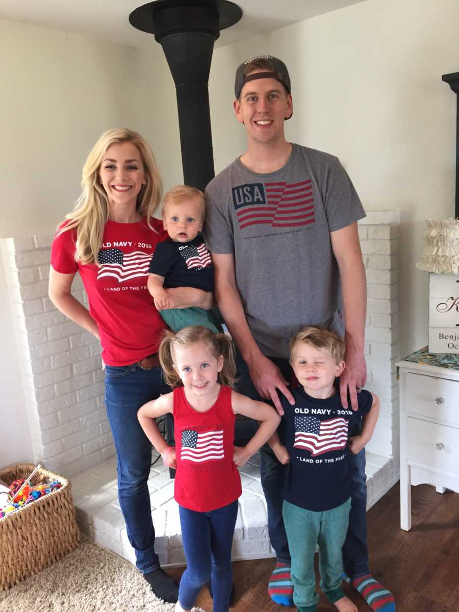 Husband and wife stand in home with their three young children