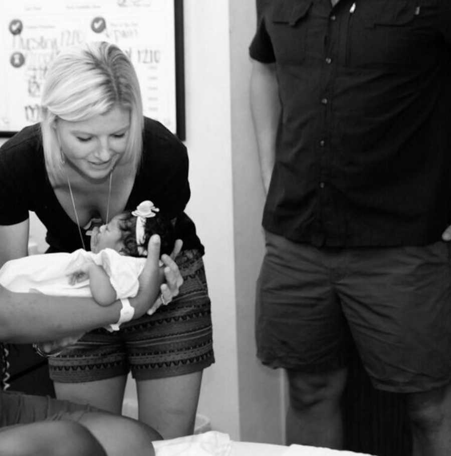 Birth mother hands newborn baby to adoptive mother