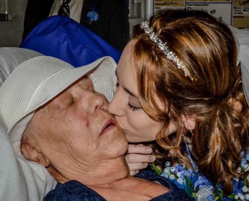 Young woman kisses cheek of grandmother who lays in hospital with lung cancer
