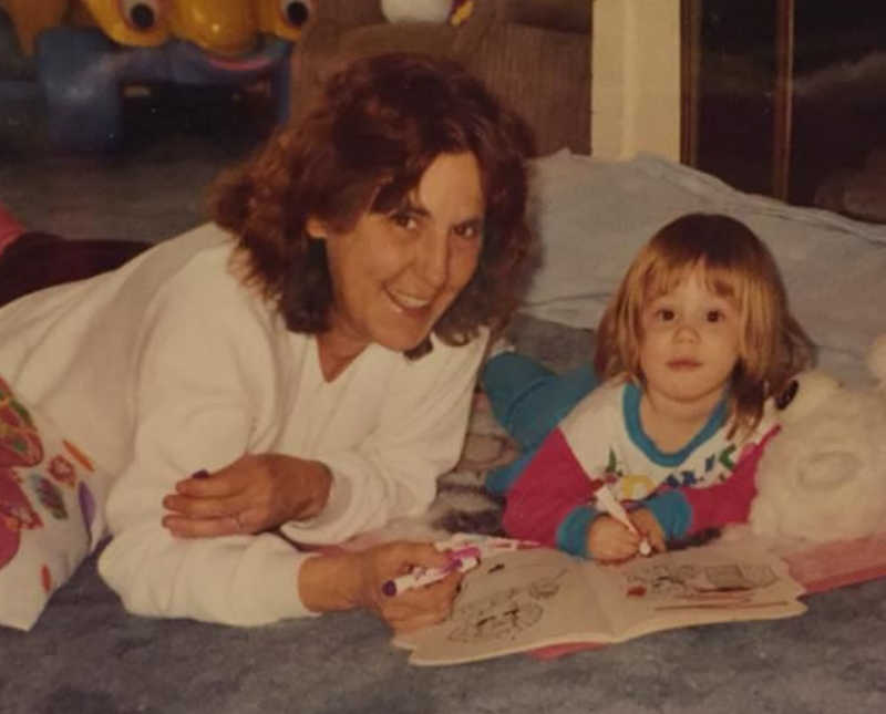 Grandmother lays beside young granddaughter on floor as they color in coloring book