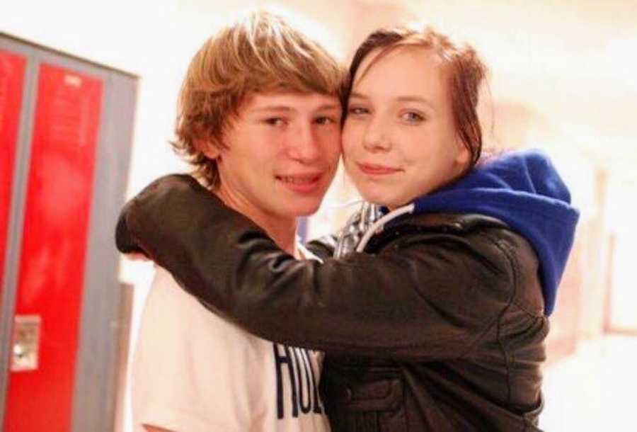 Teen boyfriend and girlfriend smile in hall of school