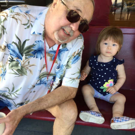 Man with stage IV cancer who has since passed sits on bench beside granddaughter