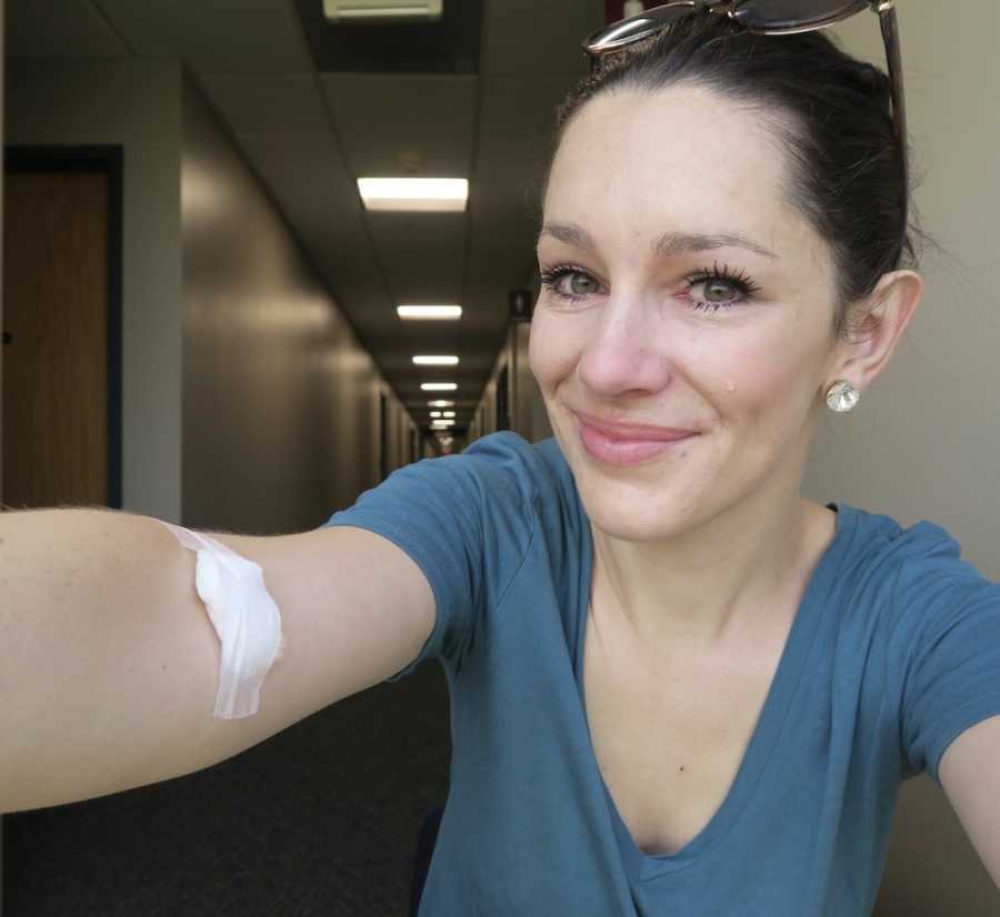 Woman with tears in her eyes takes selfie with bandage on her arm from last fertility injection