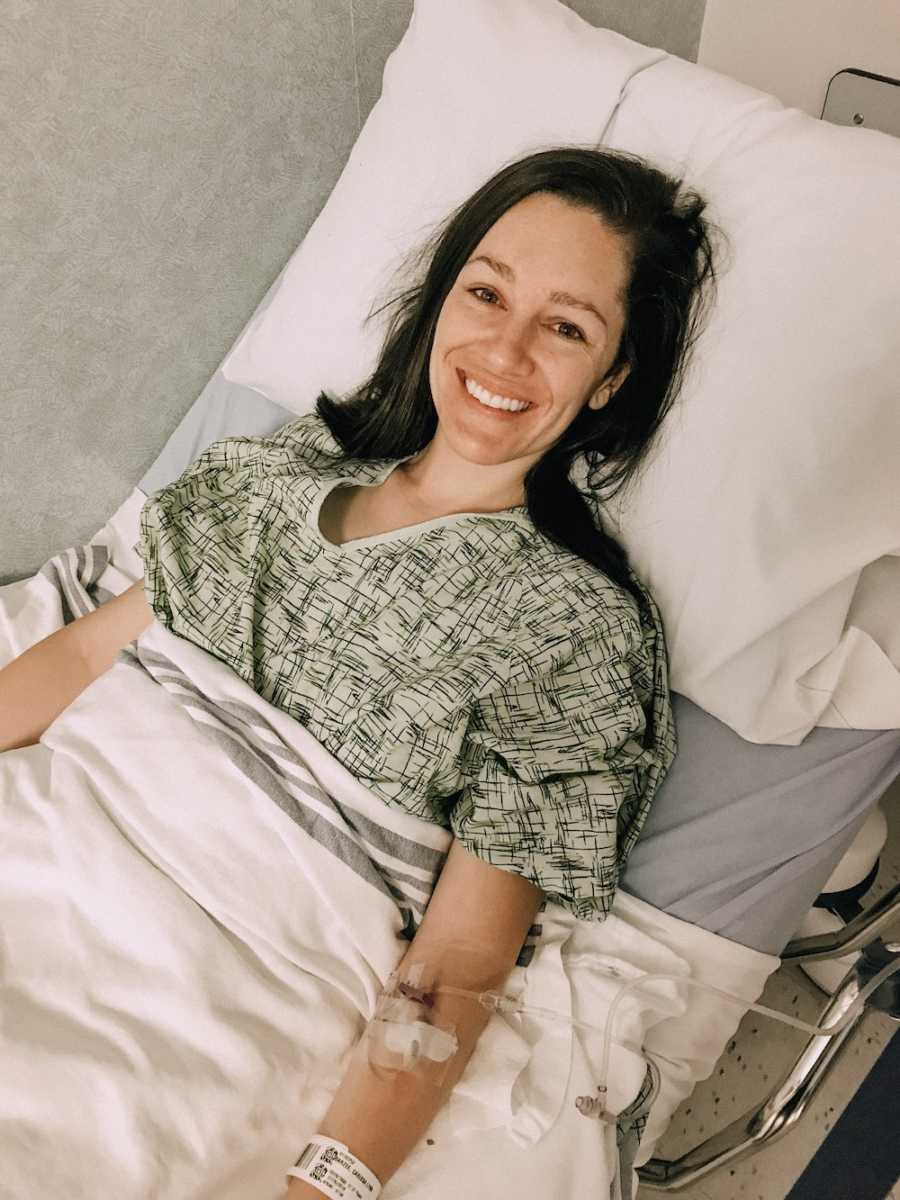 Woman lays smiling in hospital bed for egg retrieval