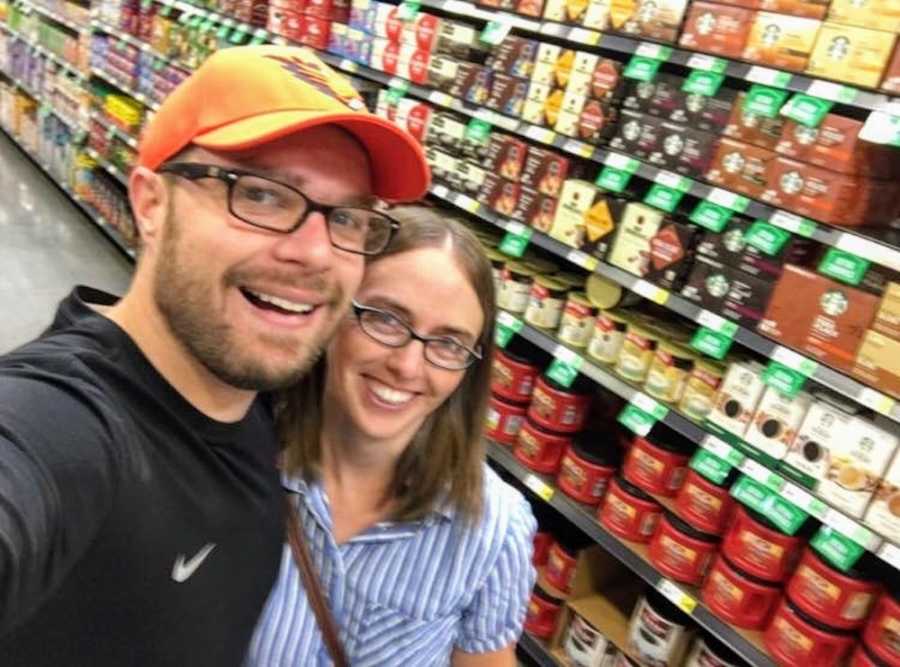 Husband and wife smile in coffee aisle of grocery store