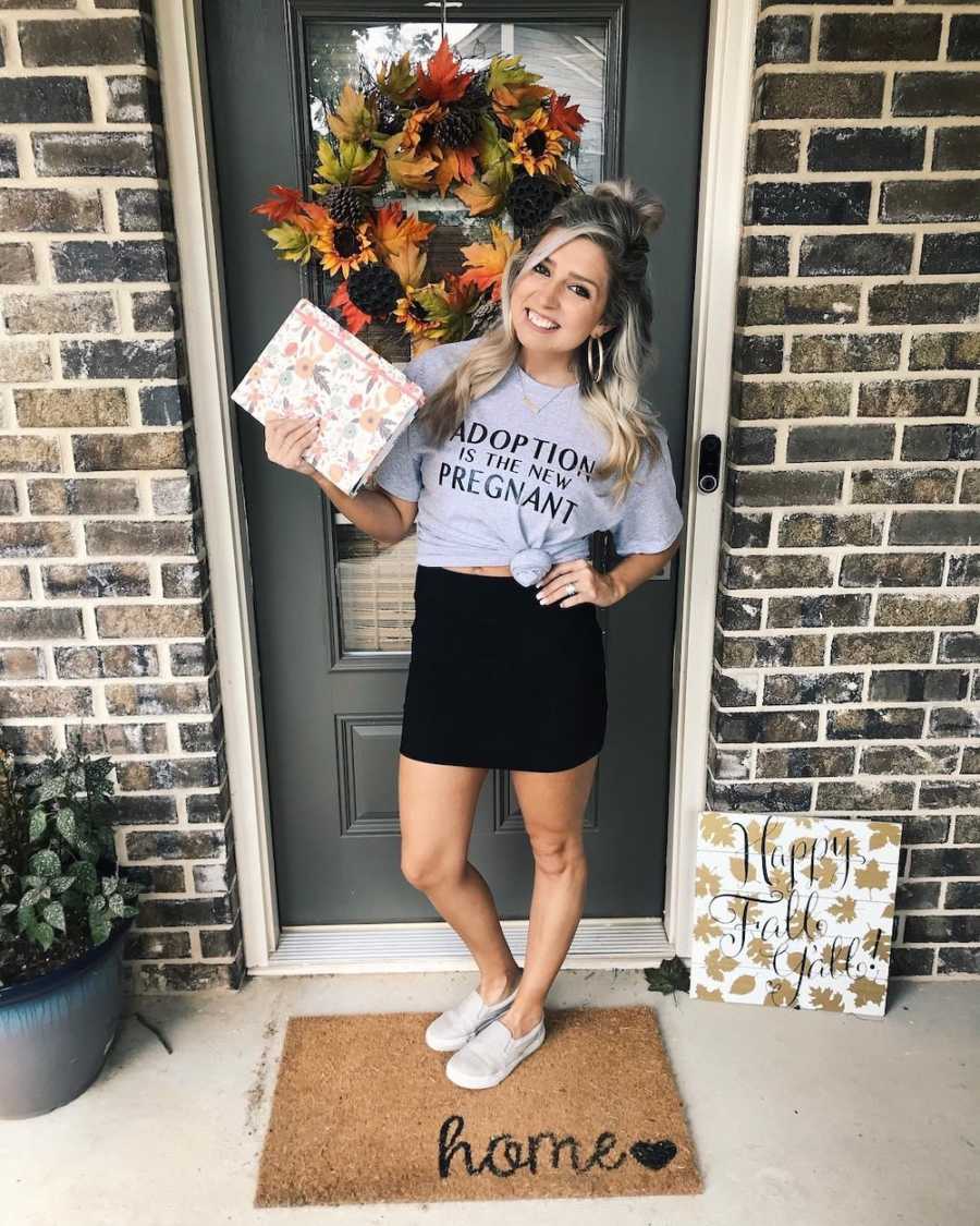 Woman stands outside of home wearing shirt that says, "adoption is the new pregnant"