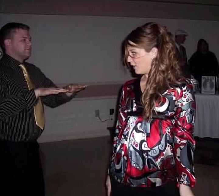 Pregnant woman looks over at husband dancing