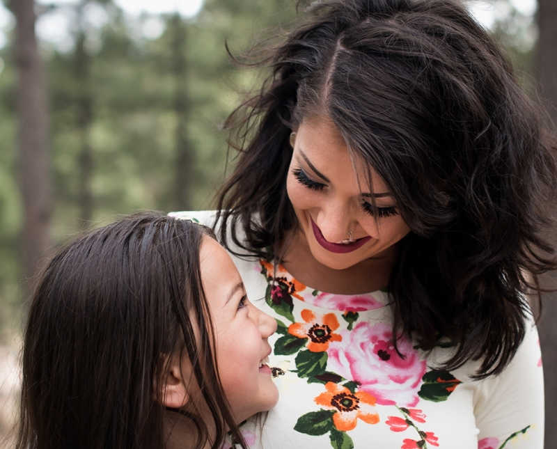 Woman who was in abusive marriage smiles as she looks down at daughter