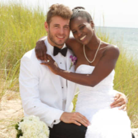 Bride who was once refugee smiles sitting on grooms lap on beach