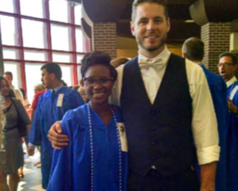 Woman who was once a refugee stands in blue graduation gown beside future husband